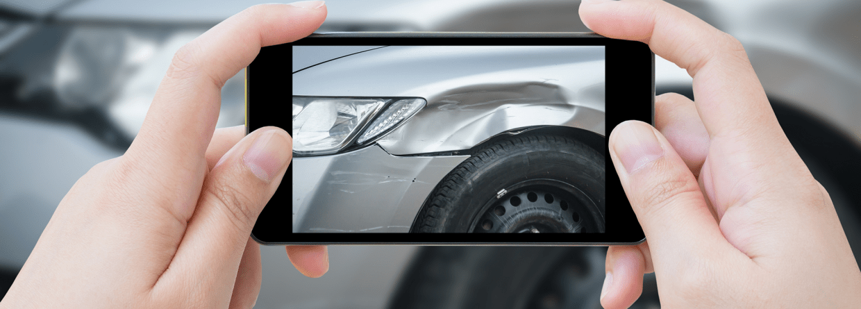 Een vrouw maakt een foto van de schade aan haar auto